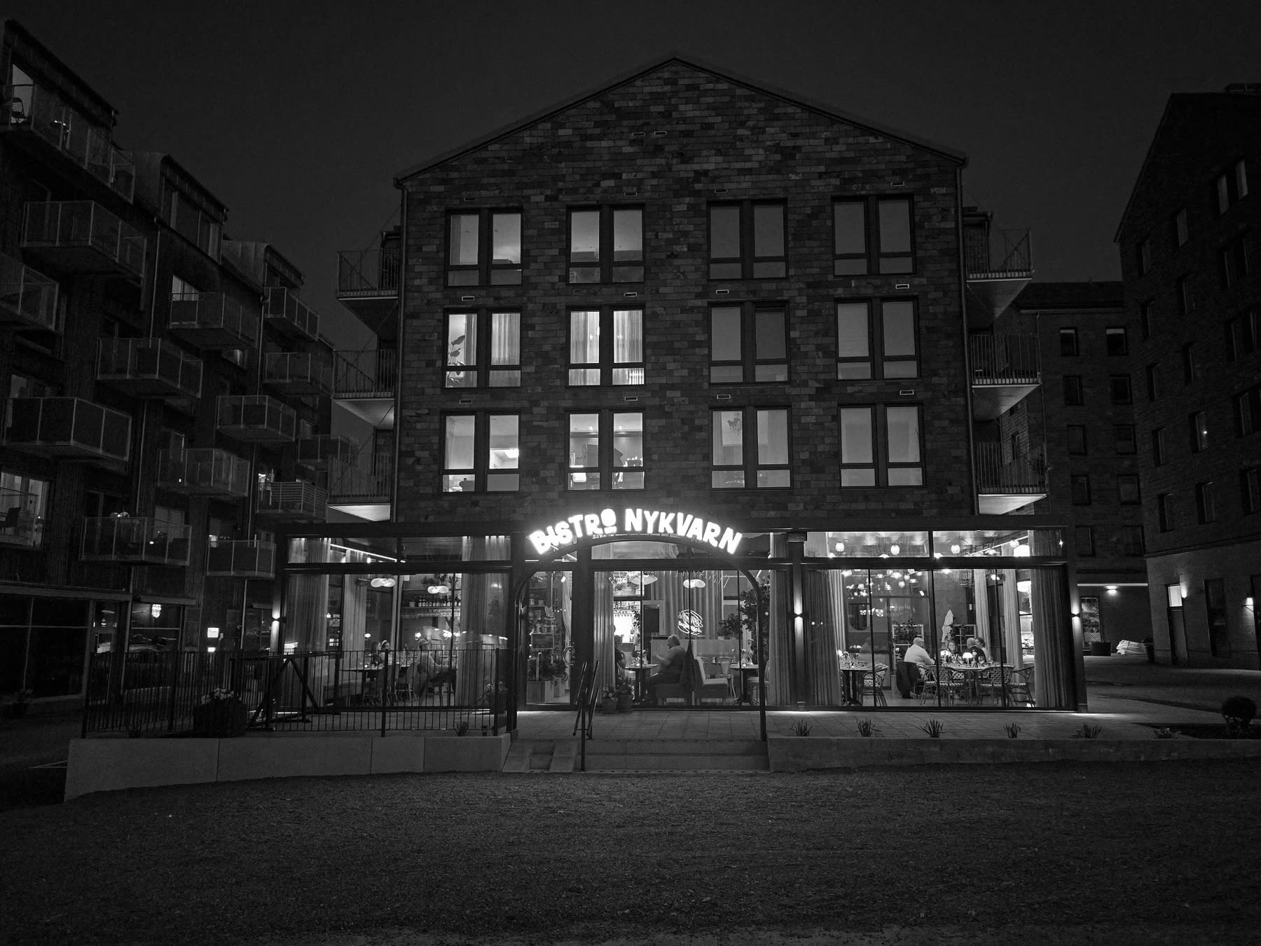 Bistro Nykvarns fasad och upplysta skylt i kvällsljus